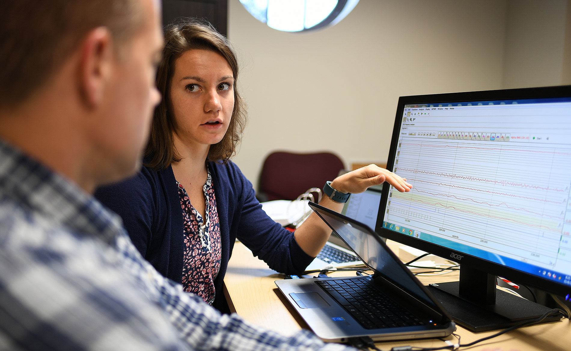 student and professor talking by a computer with brain waves