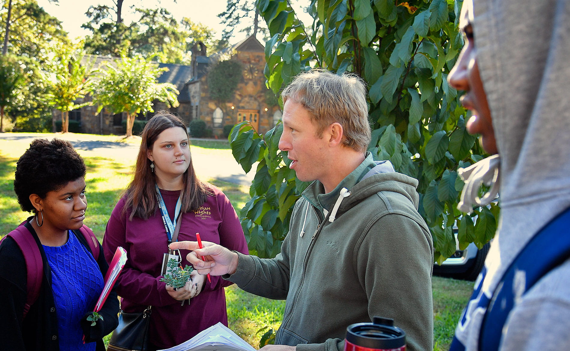 Professor lecturing to students outside in an orchard