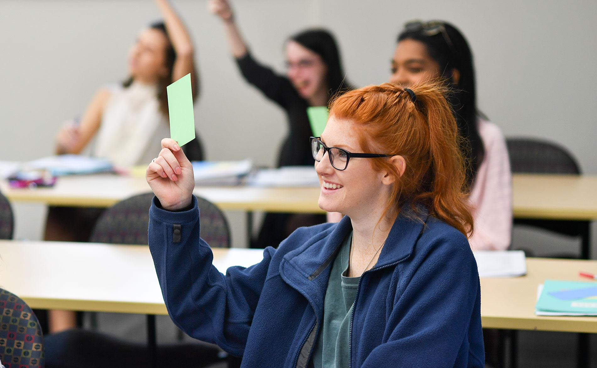 Female student holding up a card in class